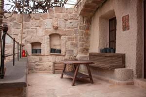 a wooden bench sitting next to a building with a table at Vintage Cave House Hotel in Göreme
