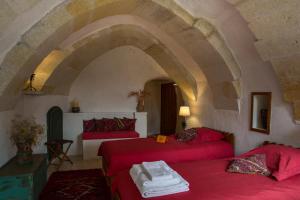 un soggiorno con 2 letti rossi e un arco di Les Maisons De Cappadoce a Üçhisar