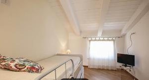 1 dormitorio con 1 cama, TV y ventana en Castellabate Apartments Mansarda Maddalena, en Castellabate
