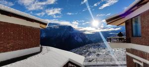 a person sitting on a balcony looking at the mountains at Casa Himalaya, Auli in Joshīmath