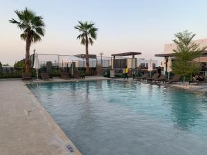 una grande piscina con sedie e palme di Spell-binding 3BR Townhouse at DAMAC Hills 2 Dubailand by Deluxe Holiday Homes a Dubai
