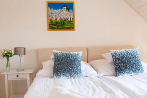 uma cama branca com almofadas azuis e uma fotografia na parede em Fiastyúk Udvarház em Csór