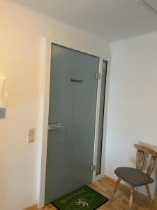 uma porta de vidro num quarto com uma cadeira e um tapete verde em Naturpark Appartment em Ratting