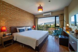 1 dormitorio con cama y pared de ladrillo en WE Valley Hotel en Chiang Mai