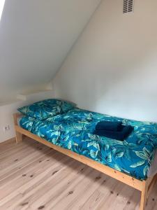 a bed in a room with a blue comforter at Klimkowskie Zacisze - domek całoroczny in Klimkówka