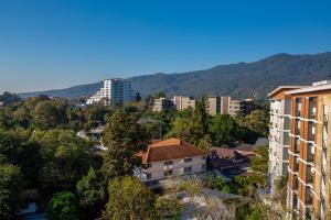 清邁的住宿－WE Valley Hotel，一座有建筑和山脉背景的城市