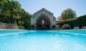 une grande piscine avec une église en arrière-plan dans l'établissement Château de Mathod Chambres d'hôtes, à Mathod