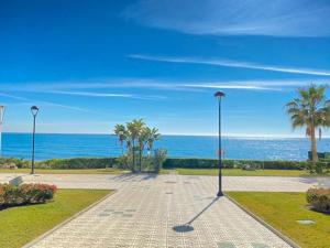 a walkway next to the ocean with palm trees at Castillo Bajo - Adults Only in Torrox Costa