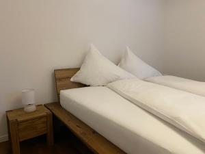 - une chambre avec 2 lits avec des draps blancs et une table de nuit dans l'établissement Ansàna, à Lenz