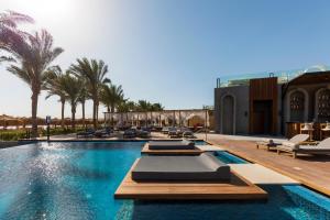 a pool at a hotel with lounge chairs and palm trees at Sunrise Tucana Resort -Grand Select in Hurghada