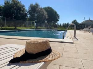 un sombrero de paja sentado en un banco junto a una piscina en Agriturismo Il Vignone en Castagneto Carducci