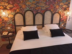 ein Bett mit weißer Bettwäsche und schwarzen Kissen im Schlafzimmer in der Unterkunft Hotel de Champagne in Épernay