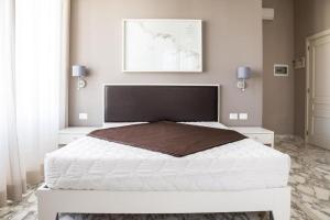 a bedroom with a large white bed and two white cabinets at Faro Bianco Gallipoli - Suites & Apartments in Gallipoli