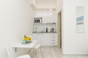 a kitchen with white cabinets and a table and a sink at Apartment Rafaello in Dubrovnik