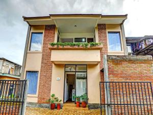 a brick house with a balcony with plants on it at Super OYO 90828 Ara Guest House in Batu