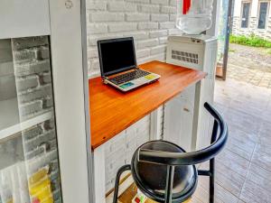 a laptop computer sitting on a wooden counter with a chair at Hotel O Ara Guest House in Batu