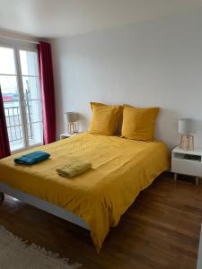 a bedroom with a bed with yellow sheets and a window at La Catène-Perret in Le Havre