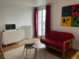 a living room with a red couch and a tv at La Catène-Perret in Le Havre