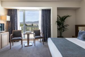 a hotel room with a bed and a desk and a window at Amalia Hotel Athens in Athens
