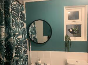 a bathroom with a mirror and a blue wall at The Velveteen Townhouse in Colchester +6 photos