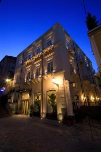 Un grand bâtiment blanc avec des lumières allumées la nuit dans l'établissement Il Principe Hotel Catania, à Catane