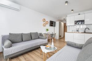 a living room with a couch and a kitchen at Apartamenty Porta Mare by Renters in Dziwnówek