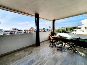 a balcony with a table and chairs and large windows at Cozy Apartment on the Beach in Sitio de Calahonda