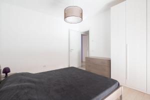 um quarto com paredes brancas e uma cama com um cobertor cinzento em Finisterrae 2 em Lido di Jesolo