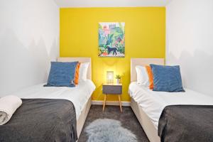 2 camas en una habitación con una pared amarilla en Queens Apartment - By My Getaways - Free Parking for one car, en Brighton & Hove