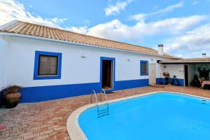 a villa with a swimming pool in front of a house at Herdade do Marmeleiro in Bicos