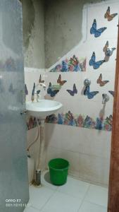 La salle de bains est pourvue d'un lavabo et de papillons sur le mur. dans l'établissement Bardia Community Homestay, à Bardiyā