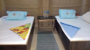 two twin beds with blue pillows on them in a room at Bardia Community Homestay in Bardiyā