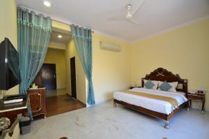 a bedroom with a bed and a piano and a television at Aaram Baagh - A Luxury Nature Resort in Udaipur