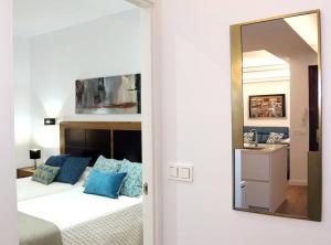 a bedroom with a bed with blue pillows and a mirror at Piso Reformado a 2 Min del Casco Viejo Con Garaje Gratis in Bilbao