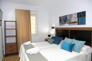a bedroom with two beds with blue pillows at Piso Reformado a 2 Min del Casco Viejo Con Garaje Gratis in Bilbao