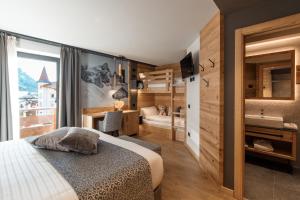 
a bedroom with a bed, a desk and a mirror at Hotel Belvedere in San Martino di Castrozza
