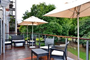a balcony with chairs and tables and an umbrella at ANEW Hotel Roodepoort Johannesburg in Roodepoort