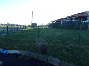 einen Zaun in einem Garten mit einem Grasfeld in der Unterkunft Apartamentos Rurales Miramar in Pimiango