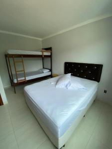 a white bed in a room with a bunk bed at Siri Mariscal Bombinhas C Piscina in Bombinhas