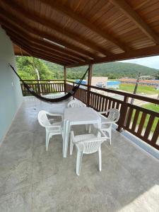 a porch with a white table and chairs and a hammock at Siri Mariscal Bombinhas C Piscina in Bombinhas
