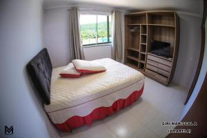 a bedroom with a bed with a window and a television at Siri Mariscal Bombinhas C Piscina in Bombinhas