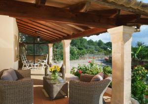 un patio con sillas de mimbre bajo una pérgola de madera en Villa Marina Malagarba By SunVillas Mallorca, en Pollensa