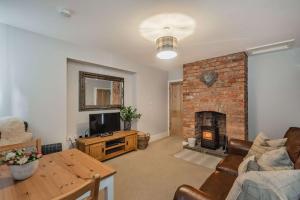 a living room with a brick fireplace and a couch at Pheasant Cottage in Tarporley