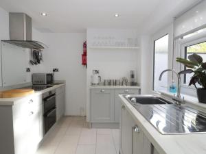 a white kitchen with white cabinets and a sink at Clock cottage in Conwy