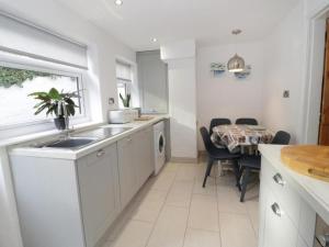 a white kitchen with a sink and a table at Clock cottage in Conwy