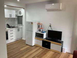 a kitchen with a refrigerator and a tv in a room at Hughesdale Private Studio in Oakleigh