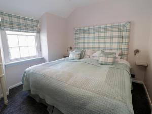 Schlafzimmer mit einem Bett mit einem karierten Kopfteil in der Unterkunft Clock cottage in Conwy