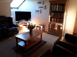 a living room with a coffee table and a tv at Greystones Lodge in Swayfield