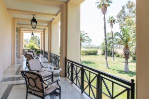 un balcone con tavoli, sedie e palme di Amalia Hotel Nafplio a Nauplia