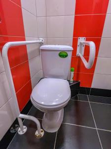 a white toilet sitting in a bathroom next to a toilet paper dispenser at London Mini-hotel in Yekaterinburg